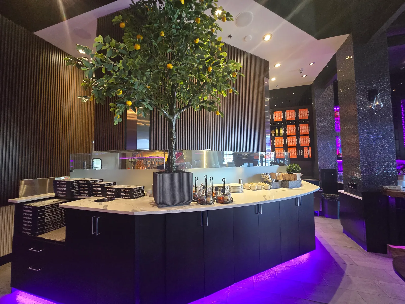 Open wood-fired pizza kitchen and takeout counter stacked with THE PIZZA SPOT boxes at our West Edmonton Mall location